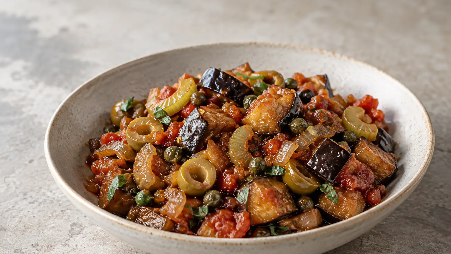 Caponata with browned eggplant, green olives and capers in glossy tomato sauce