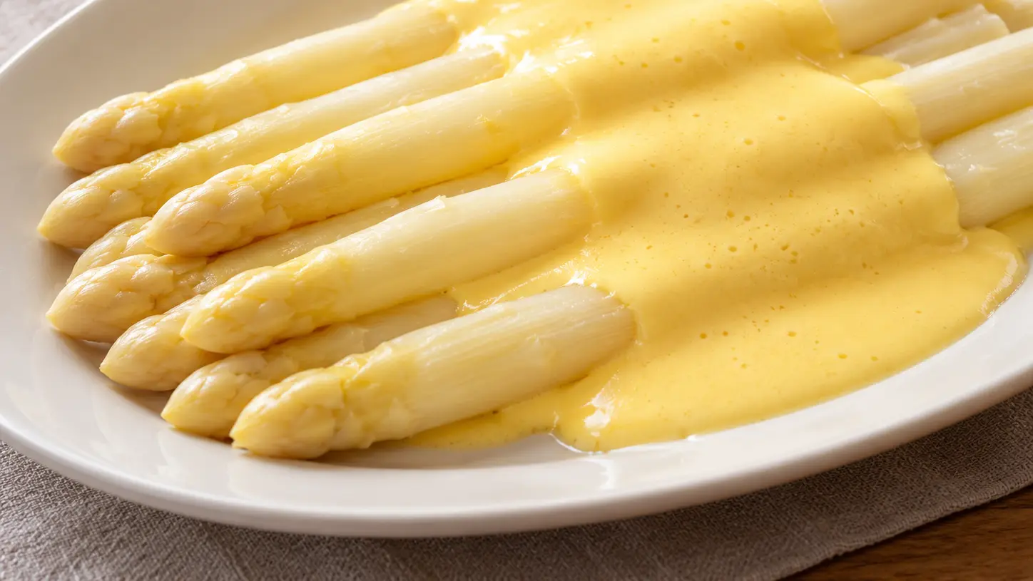 Asparagi bianchi nel piatto sotto salsa olandese vellutata giallo chiaro senza altre decorazioni