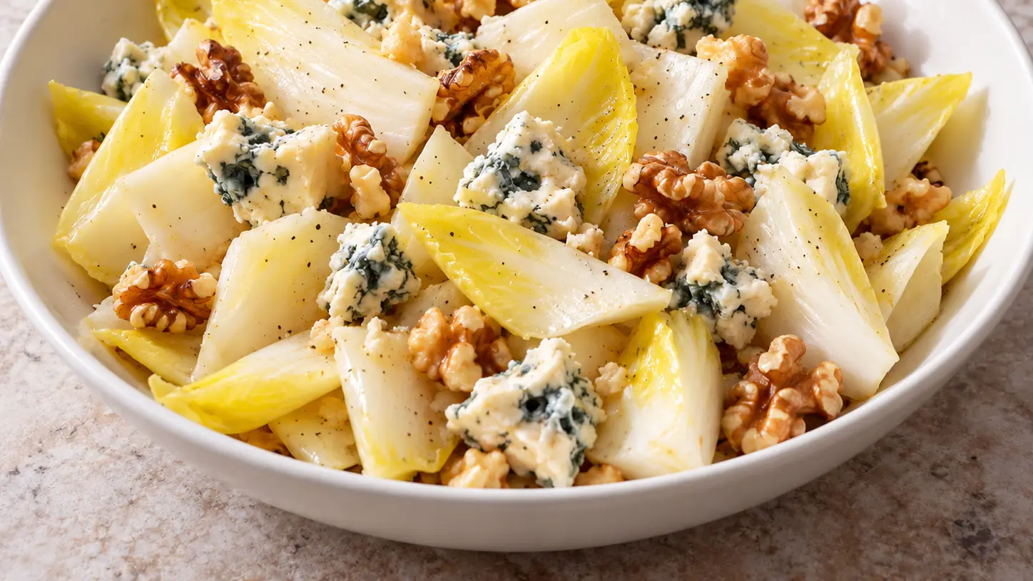 Salade van witte witlof met stukken roquefort van schapenmelk en licht geroosterde walnoten