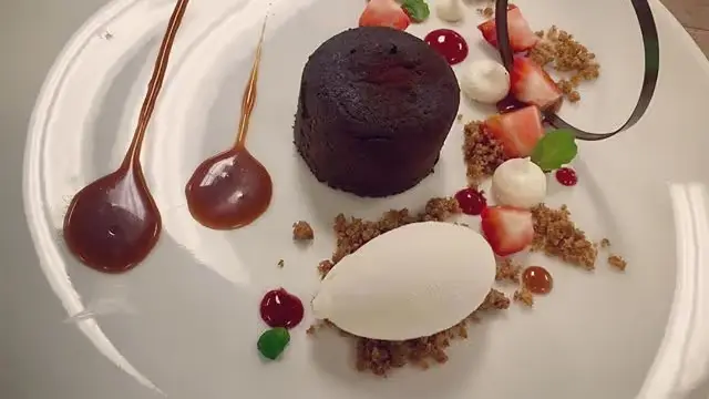 Czekoladowy fondant z lodami, truskawkami, kruszonką i dekoracyjnymi kroplami sosu